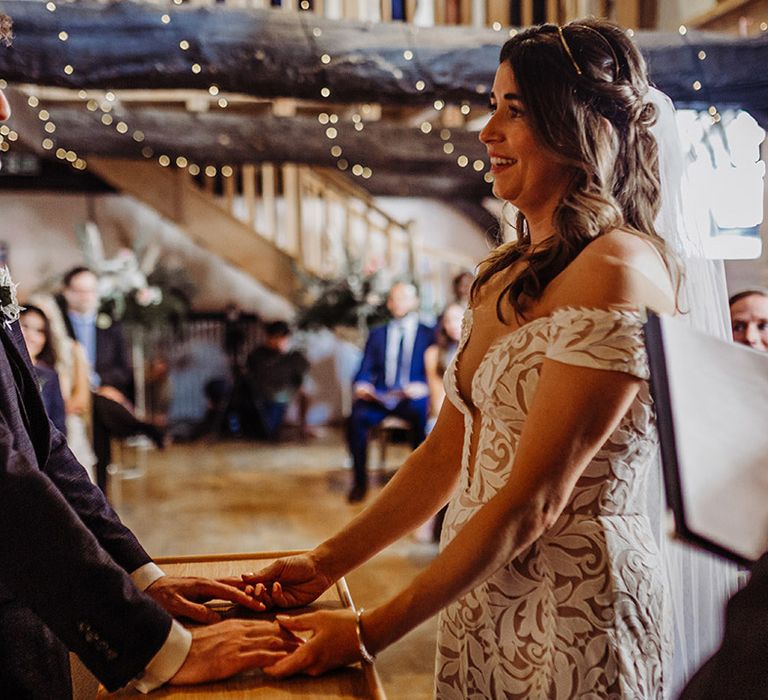 Bride looks adoringly at the groom in a blue suit as they hold hands for their wedding ceremony 