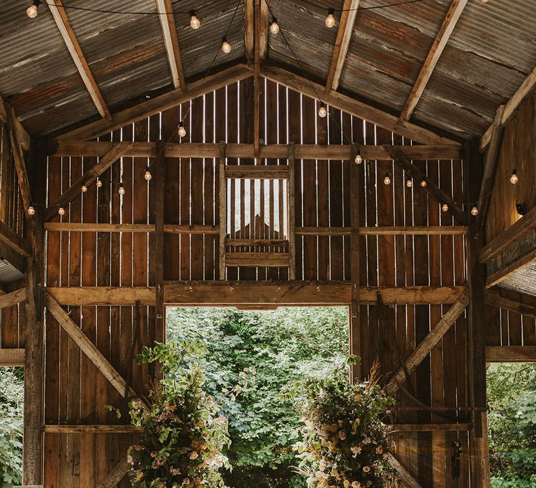 Rustic Nancarrow Farm wedding venue with two flowers columns for altar decoration and wooden chairs 