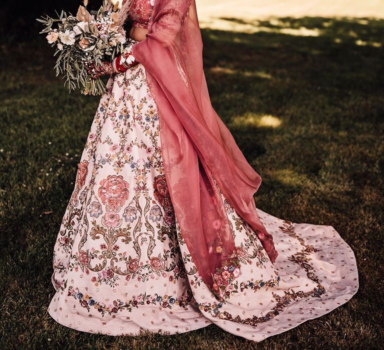 Bride wears beautifully embellished pink lehenga complete with floral inspired design 