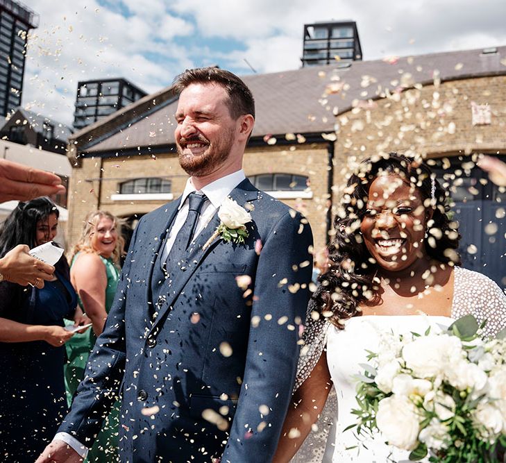 Bride & groom walk through confetti outdoors on their wedding day at Trinity Buoy Wharf 