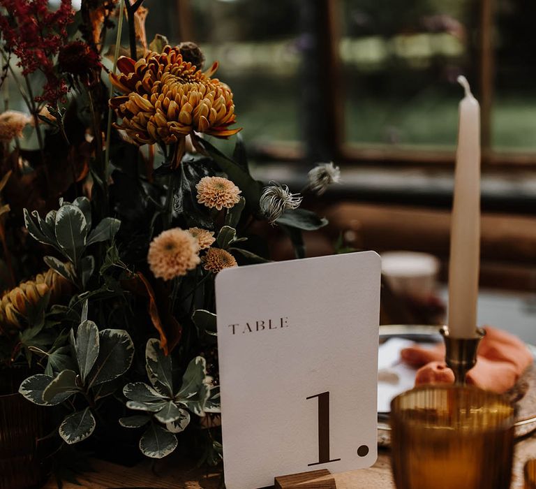 White simple and minimal table name next to the autumnal flower centrepiece 