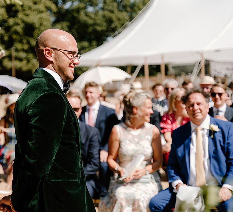 Groom wears green velvet black tie during outdoor wedding ceremony