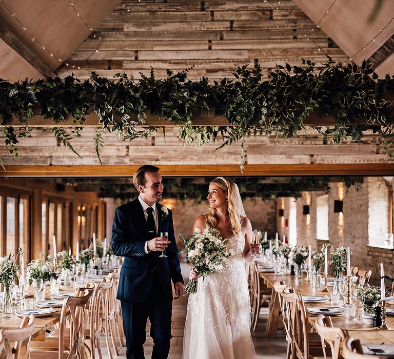 Old Gore Barn wedding venue decorated with classic greens and whites with the bride and groom standing in the aisle 