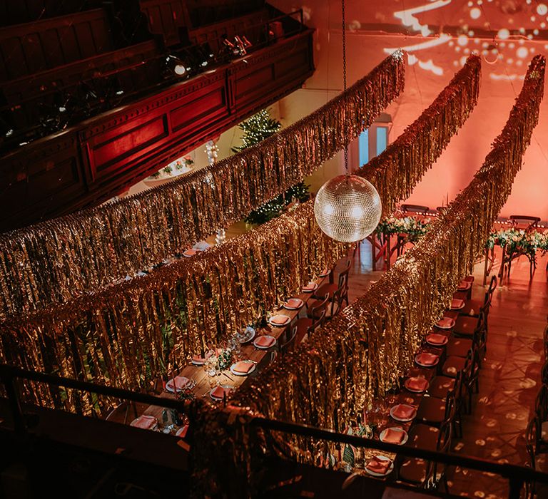 Gold wedding streamers, large hanging disco ball, Christmas tree projection and large Christmas tree in reception room of Old Marylebone Town Hall wedding venue