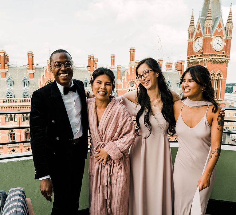 Bride stands with her mixed bridal party with bridesmaids in pale pink Rewritten bridesmaid dresses in different styles