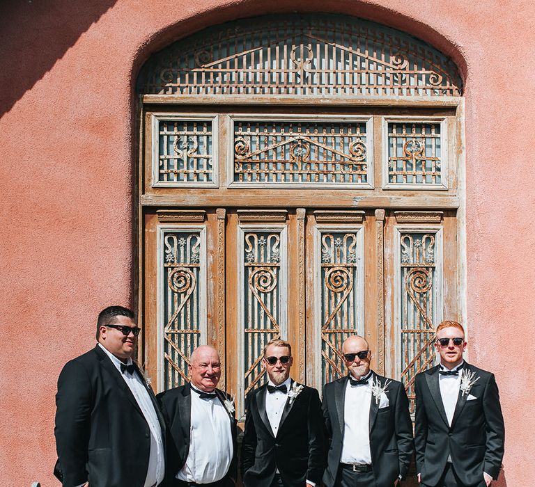 Groom and groomsmen in black tie with dried flower buttonholes and black sunglasses at Le Petit Chateau wedding venue 