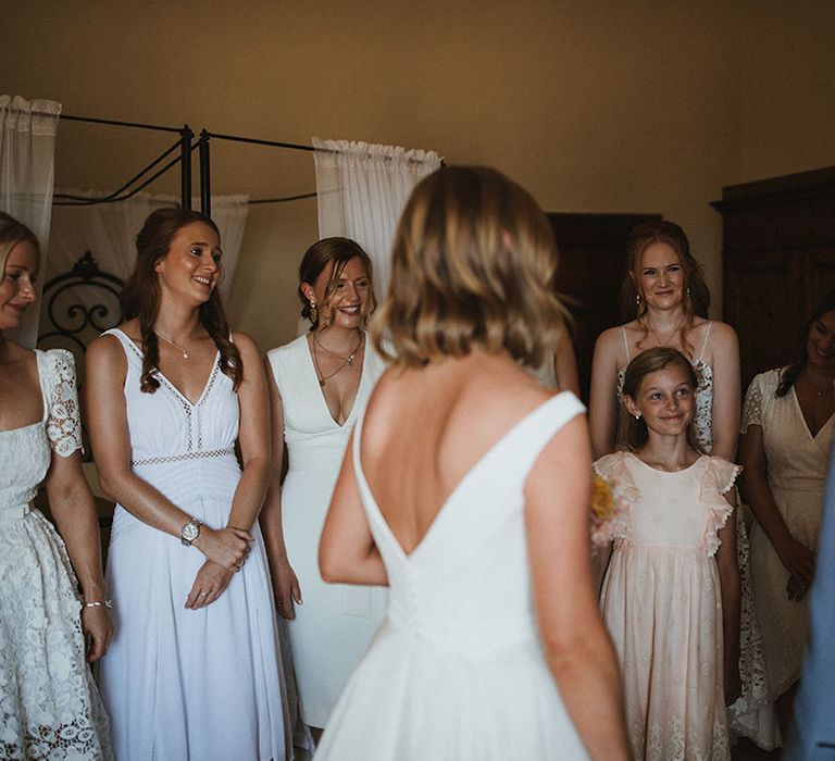 Bride stands before her bridesmaids in mismatched white bridesmaid dresses 