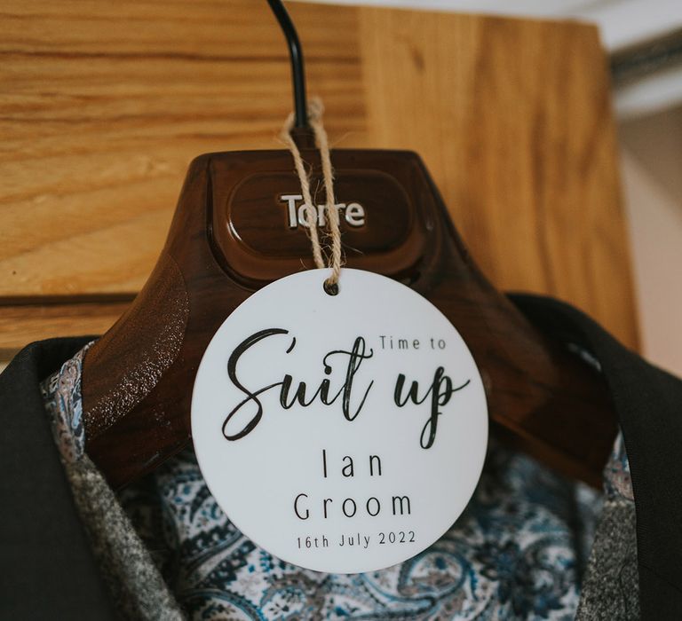 Personalised white round label tag on the hanger for the groom's suit for the morning of the wedding 