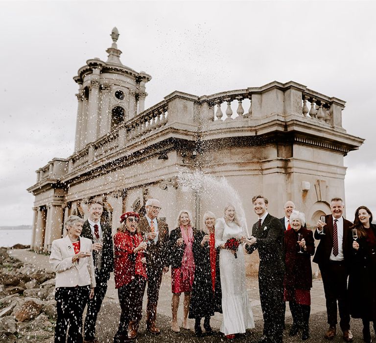 Champagne popping moment at Normanton Church with the small intimate number of wedding guests 