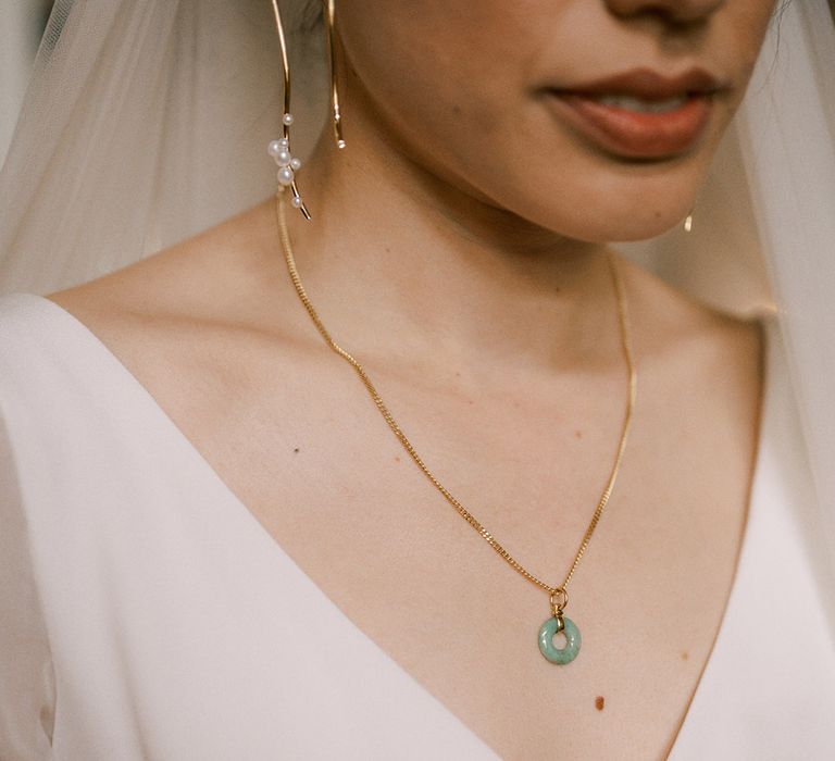 Bride wearing dainty gold necklace with jade ring for the wedding day with pearl earrings 