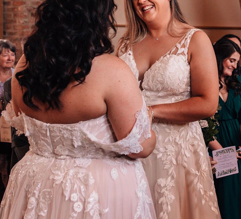 The two brides stand facing one another for their civil ceremony at The Oakwood at Ryther 