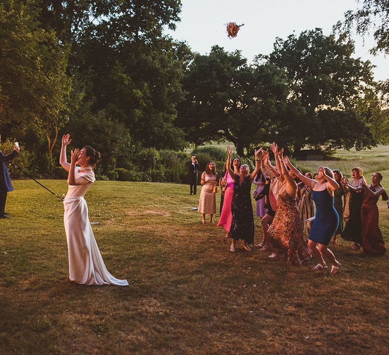 The bride performs a bouquet toss to the other bridesmaids and female guests at the wedding 