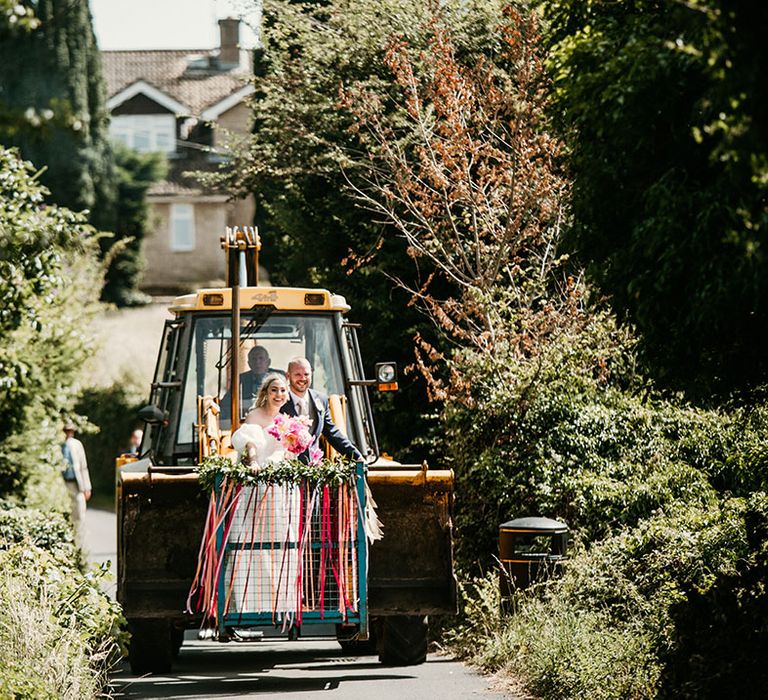 The bride and groom ride in the JCB wedding transport over to the reception driven by the bride's grandad 