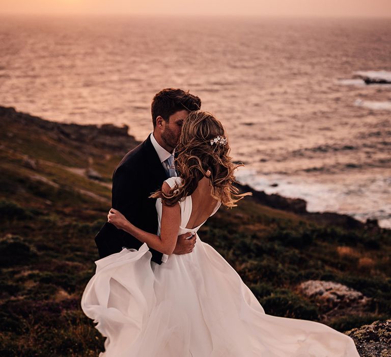 romantic Sennen cove wedding photographs with bride in a Suzanne Neville wedding dress billowing in the wind 