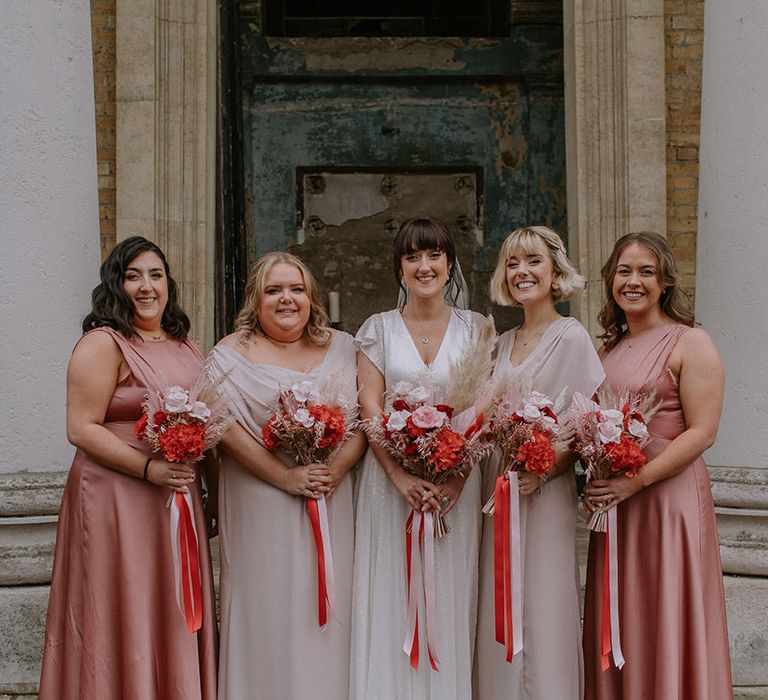 Bridal party wearing pink mismatched bridesmaid dresses for the London city wedding carrying matching bouquets 