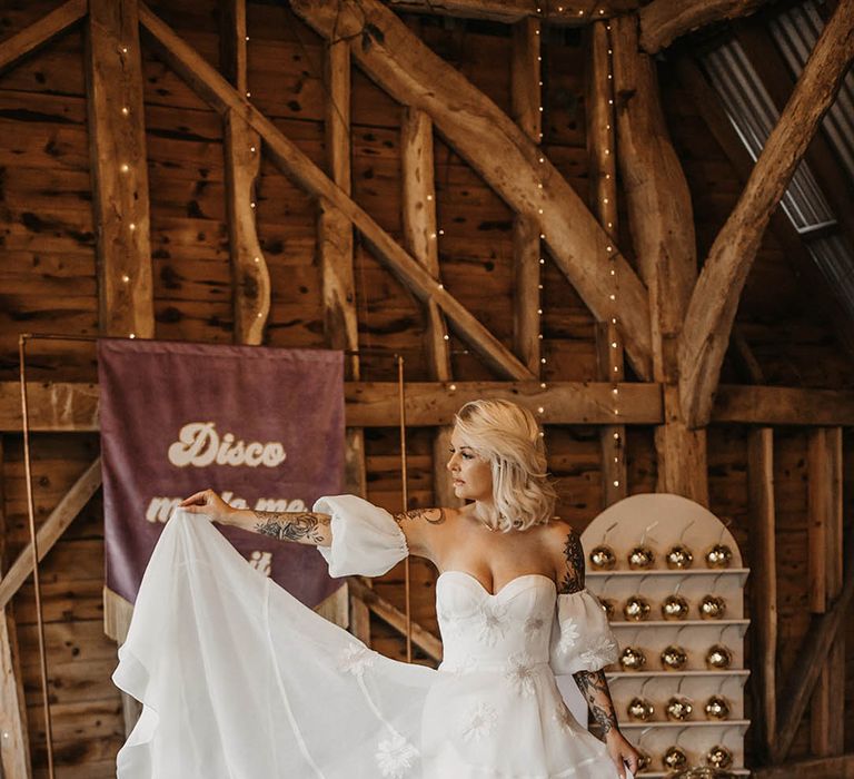 Bride in corset style daisy embroidered Freda Bennet Brady wedding dress in front of banner sign 