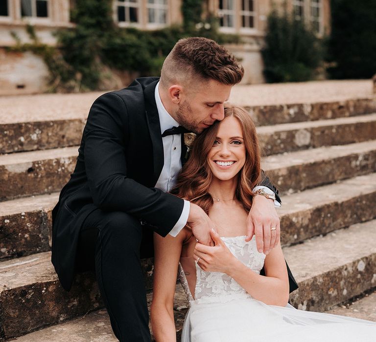 Bride in wedding dress holding a white wedding bouquet smiling with the groom 