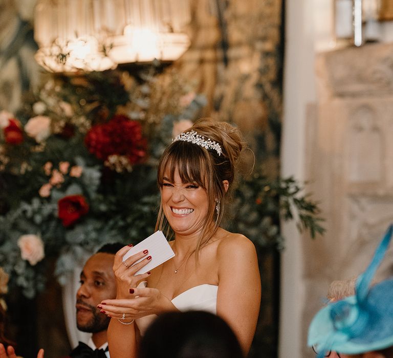 The bride stands up in her strapless wedding gown and crystal tiara with cue cards for the bridal speech 