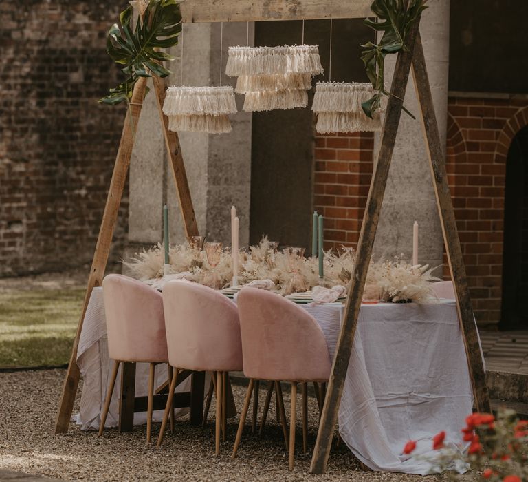 Intimate tablescape with pink velvet chairs, wool chandeliers and tropical wedding flower arrangements 