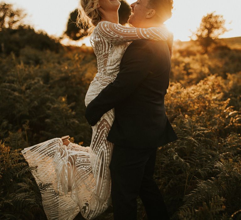 Groom picking his bride up in a preloved wedding dress and sandals 