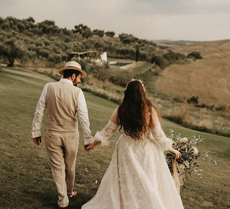 Bride and Groom holding hands with Olive bouquet after wedding