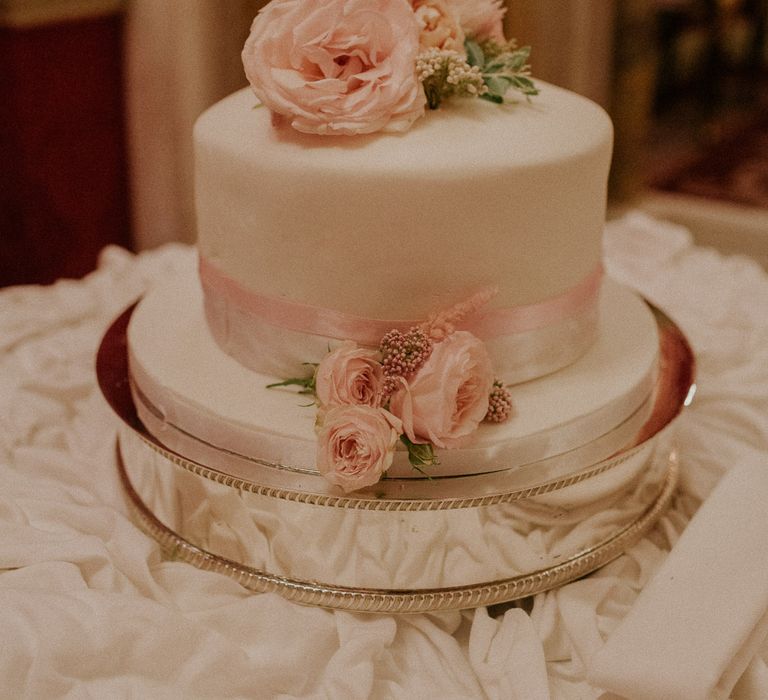 White wedding cake with pink bow and pale pink rose