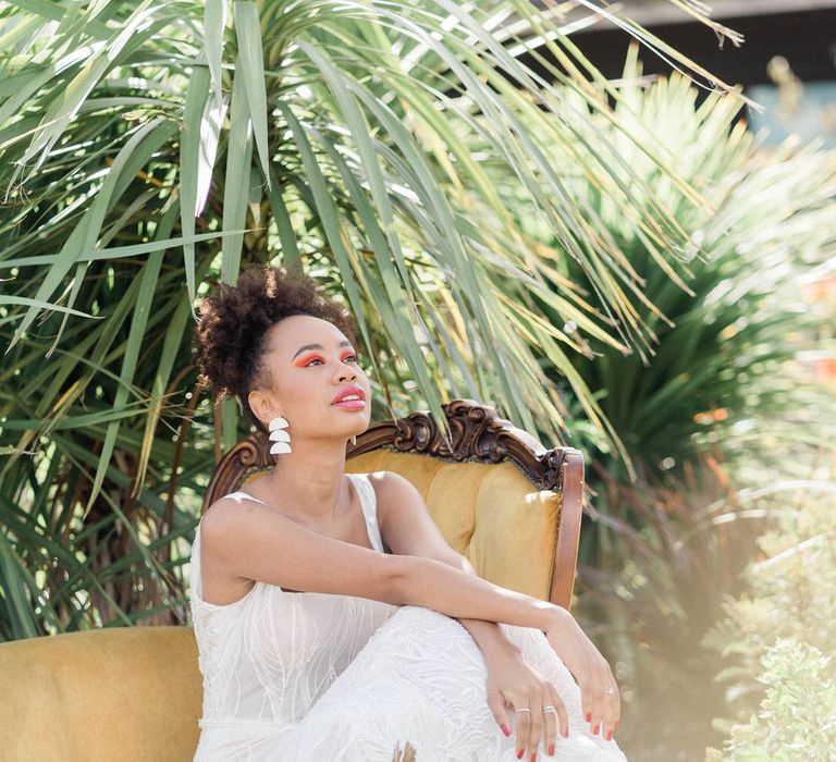 Bride in Forrest by Rachel Rose Bridal dress on yellow velvet yellow armchair in exotic garden at Urban Jungle Suffolk