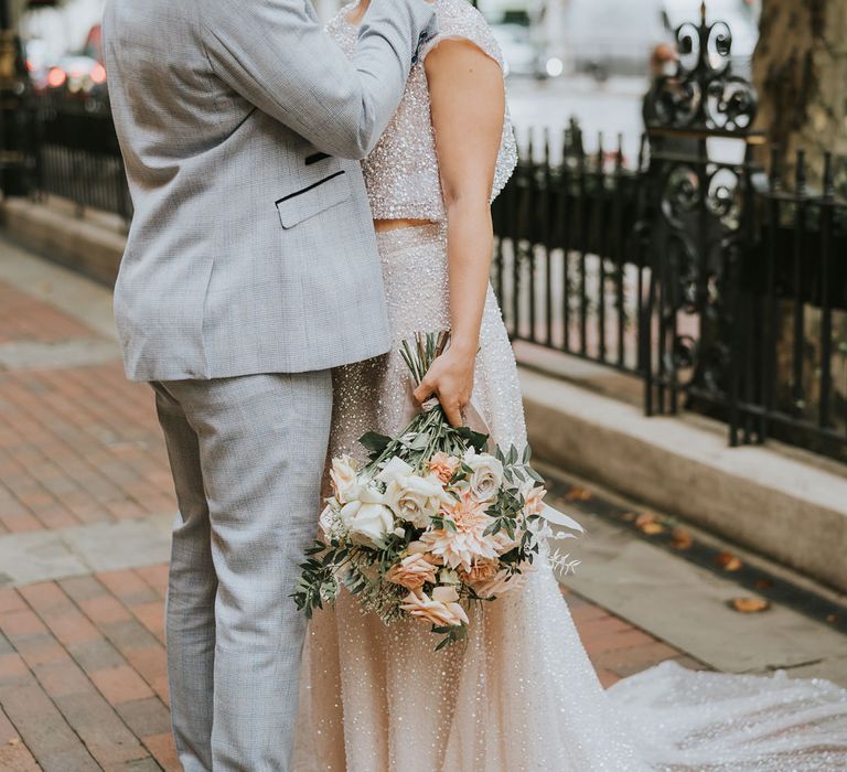 Portrait of a black groom in a light grey suit with blue check gently caressing his brides face who wears sparkly bridal separates 