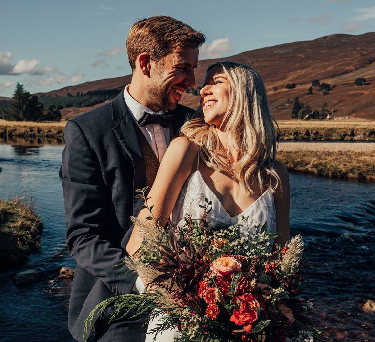 Bride & groom with lake and hills in background 