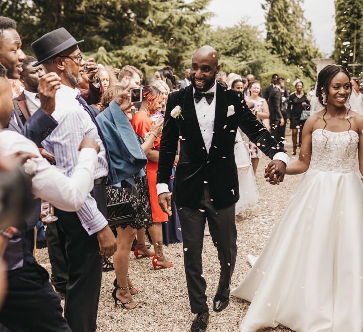 Confetti moment with Black groom in a velvet tuxedo jacket and Black bride in a strapless Oleg Cassini wedding dress with beaded bodice