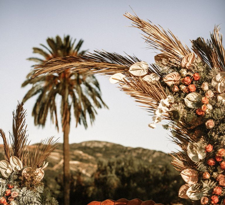 Orange velvet love seat with scalloped back at the altar with boho wedding flowers decor 