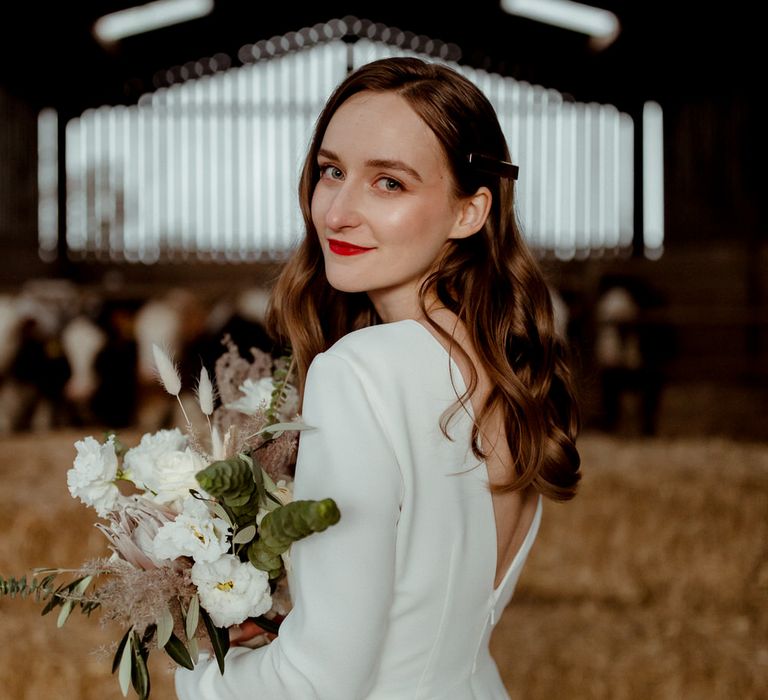 The bride posing in a barn with a group of cows