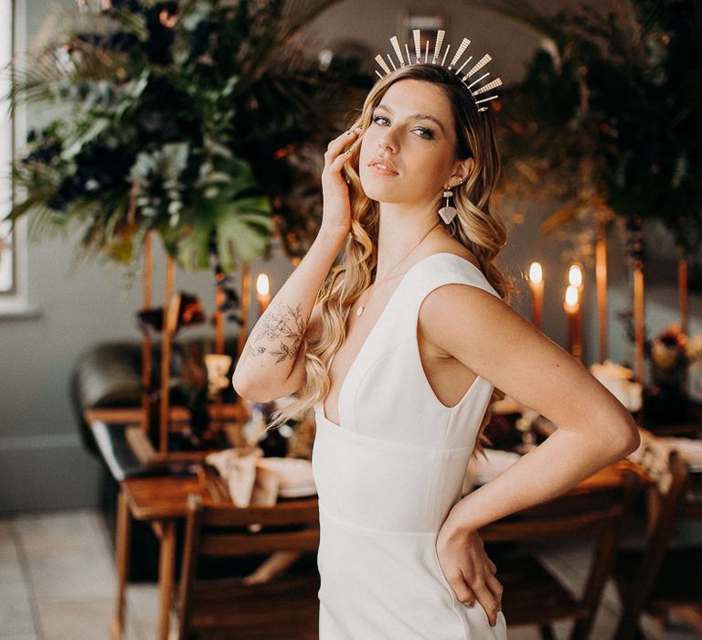 Bride in a fitted wedding dress with long wavy hair wearing a gold Tilly Thomas Lux crown 