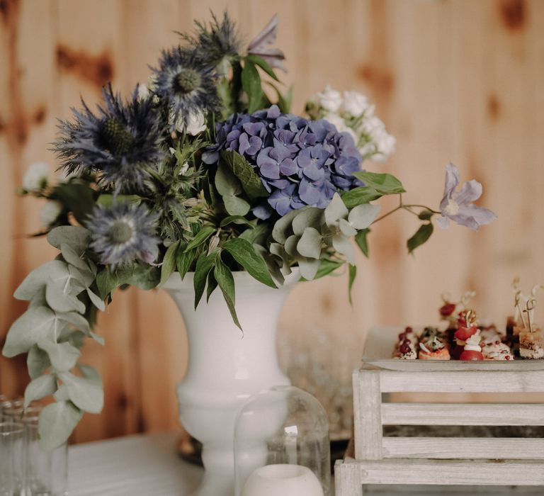 A vase of purple hydrangeas, thistles and eucalyptus leaves 