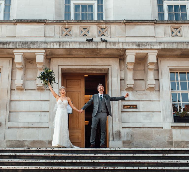 Bride & groom celebrate on the steps of Hackney Town Hall after wedding ceremony