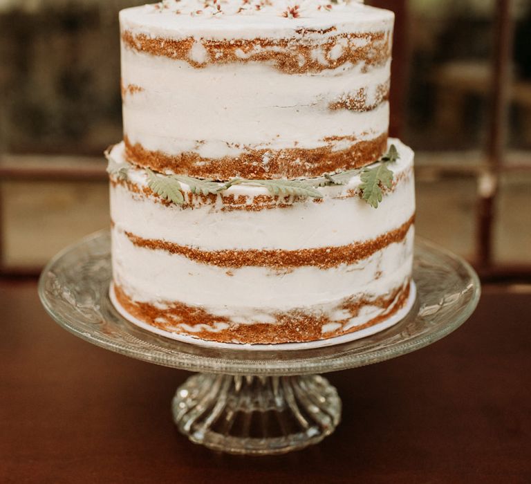 Two tier semi-naked wedding cake on glass cake stand 