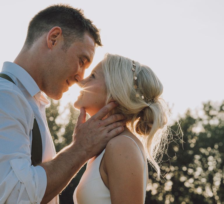 Bride & groom kiss during post-wedding photoshoot outdoors in field