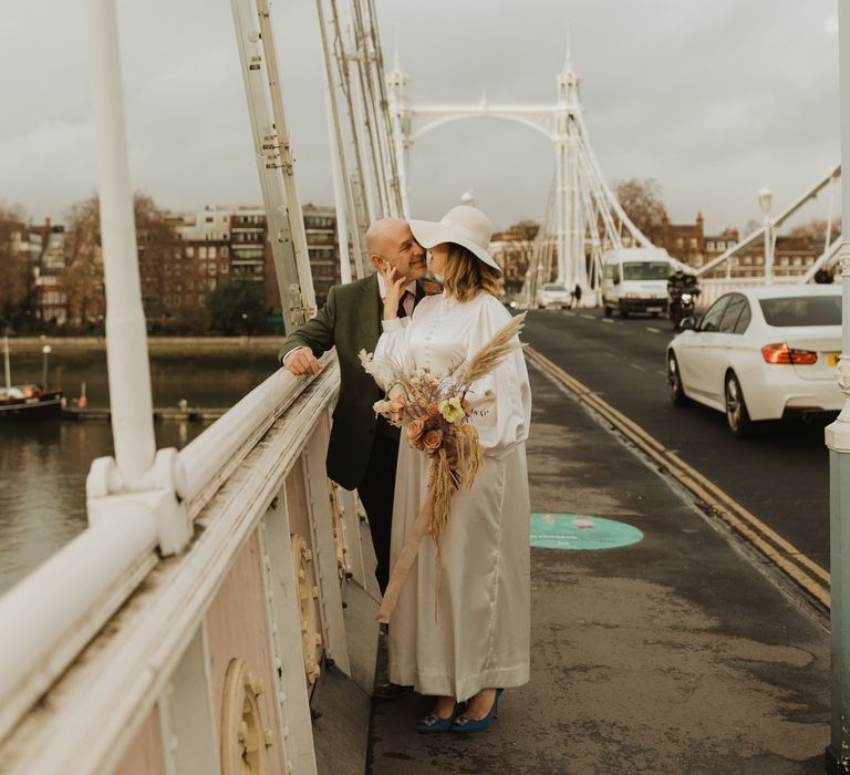 Bride places hand on grooms face as they lean in to kiss