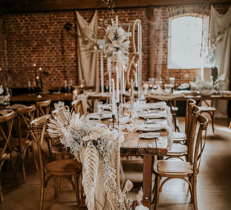 Fresh and dried flower floral arrangement on the end of a reception table with gerberas, anemones and ferns 