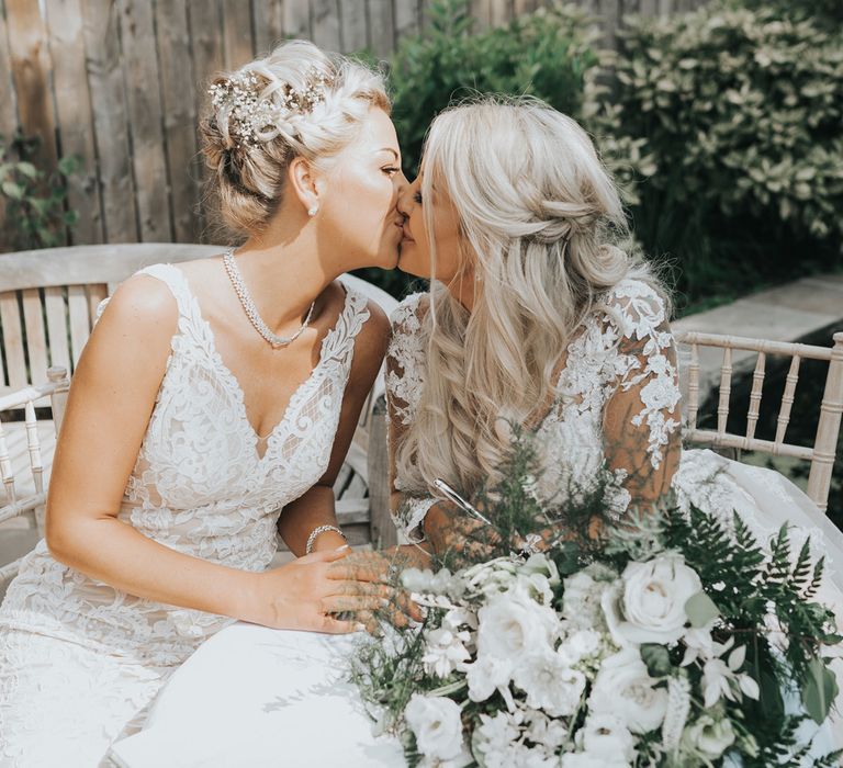 A lesbian couple kiss during a wedding portrait session. 