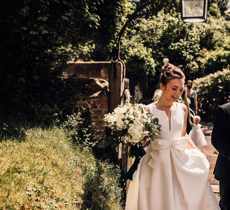 Bride wears elegant wedding gown with bow to the front