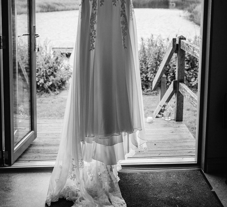 Brides Justin Alexander gown hands in front of window before wedding ceremony