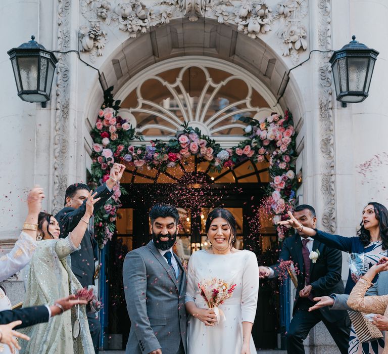 Bride & groom leave Chelsea Old Town Hall as wedding guests look on and throw confetti 