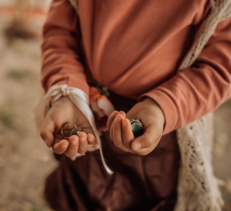 Little girl holds out wedding rings for outdoor ceremony in Sicily 