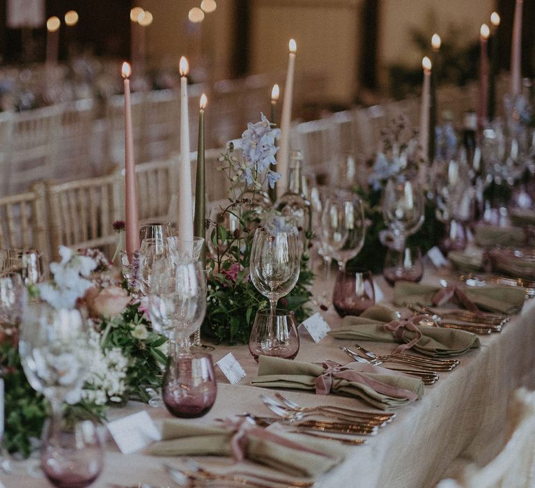 Long wedding breakfast table with pink, green and white candles, green napkins, pink glassware and wild English flowers for Loseley Park wedding in Surrey