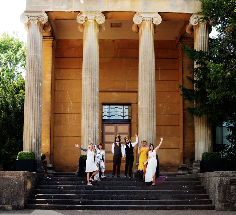 Grooms stand with wedding party outside historic building with pillars