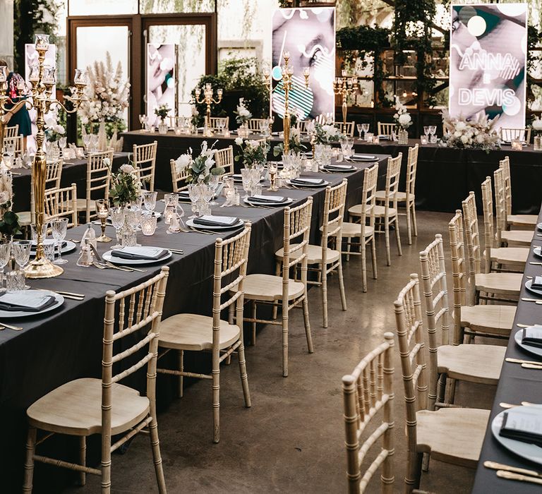 Beautifully romantic reception complete with dark tablecloths, golden chairs and hanging chandeliers in birdcages 