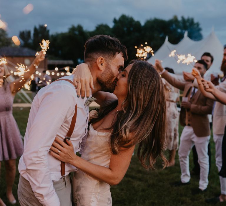 Bride & groom kiss as wedding guests hold sparklers around them for nighttime reception | Mark Bamforth Photography