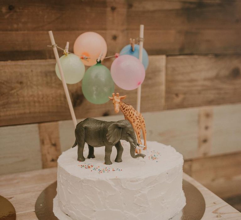 Single tier wedding cake with miniature balloons and safari animals for the cake topper 