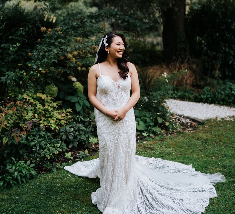 Beautiful South Asian bride with side swept long hair in an embellished wedding dress with long train and spaghetti straps 